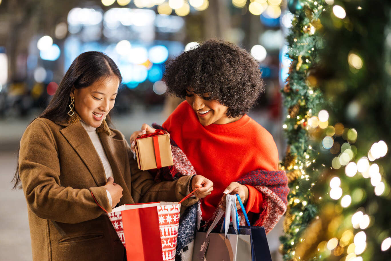 duas jovens sorridentes trocando presentes de natal